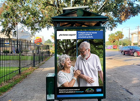 An advertisement on a bus stop that displays to older adults and displays text in spanish about getting a COVID-19 vaccine