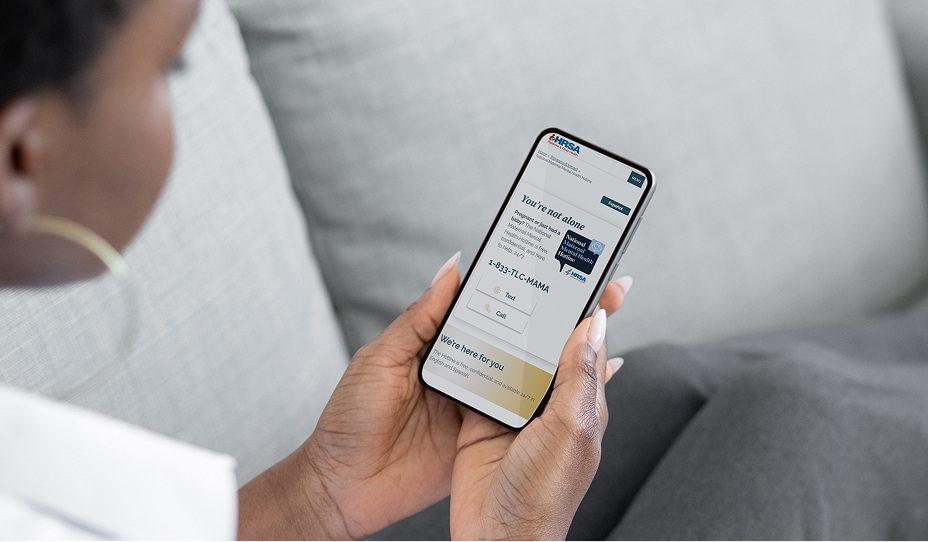 Person looking at a HRSA webpage on phone, the webpage has contact information and 1-833-TLC-MAMA as the phone number