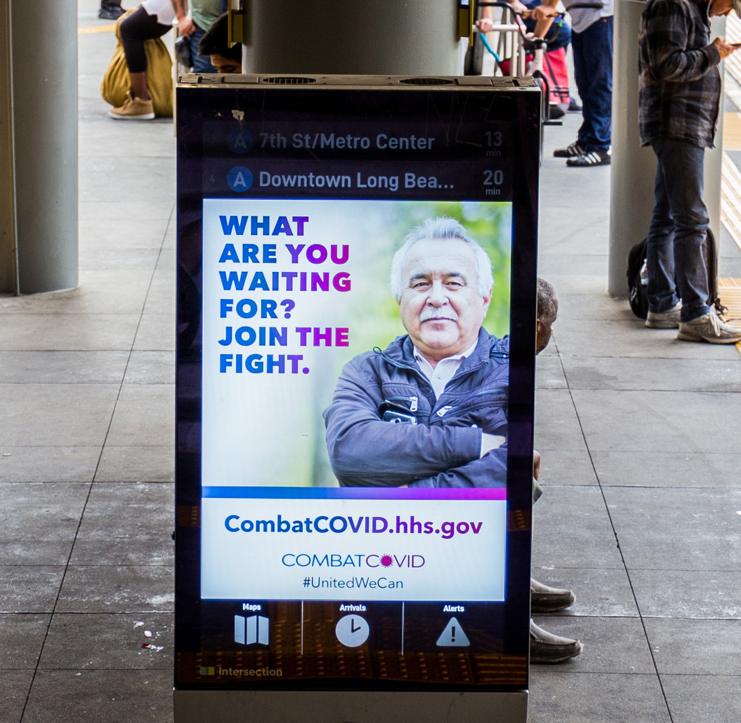 Bus kiosk ad with the text what are you waiting for? Join the fight. CombatCOVID.hhs.gov with the combat covid logo and hashtag united we can.