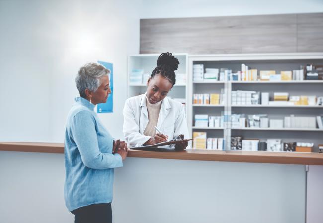 Pharmacist holding clipboard and explaining medications to person