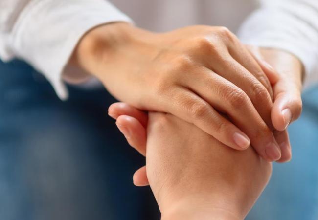 One person holding another persons hands as a comfort gesture
