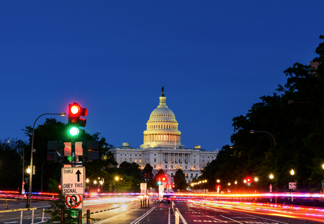 U.S. Capitol building at dusk with traffic light and long-exposure vehicle lights along a city street