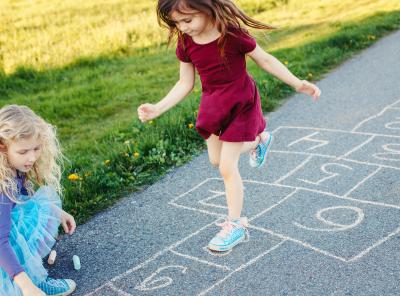 Girls playing hopscotch outside on a sunny day